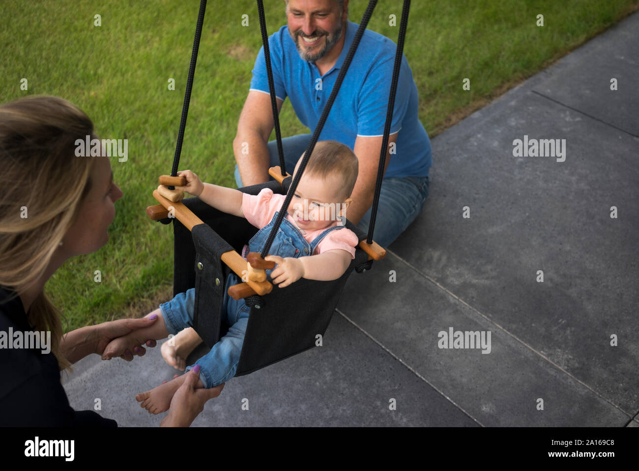 La famiglia felice con la bambina in uno swing Foto Stock