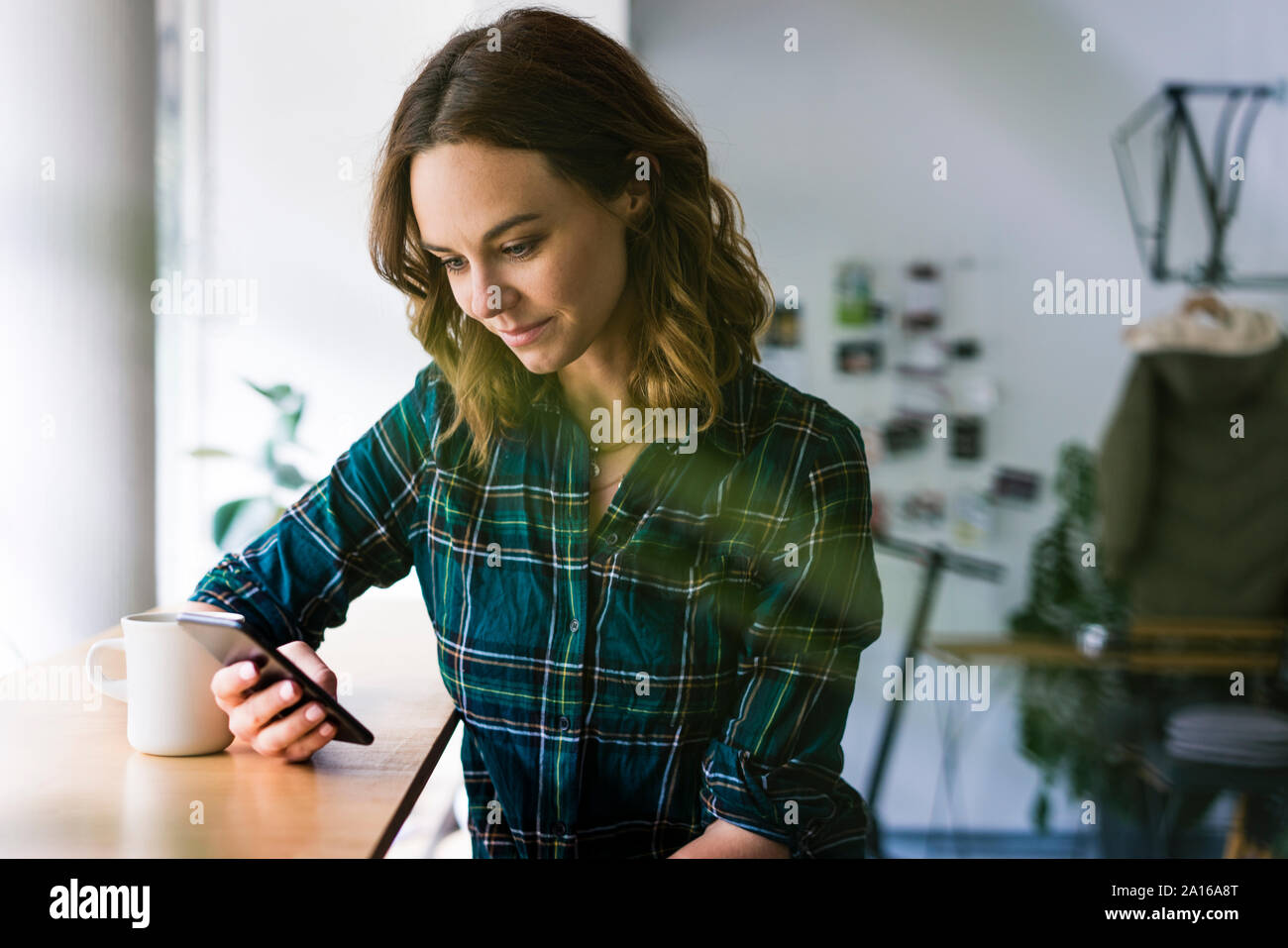 Giovane donna seduta in un coffee shop, utilizza lo smartphone Foto Stock