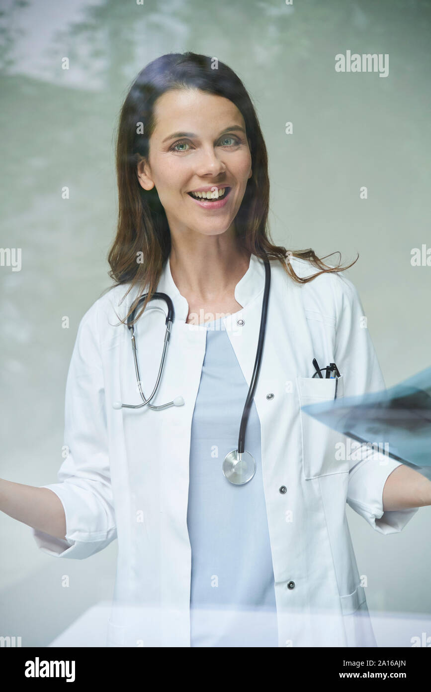 Ritratto di felice medico donna con immagine a raggi x dietro il vetro di finestra Foto Stock