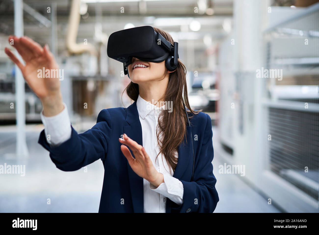 Imprenditrice indossando occhiali VR in fabbrica Foto Stock