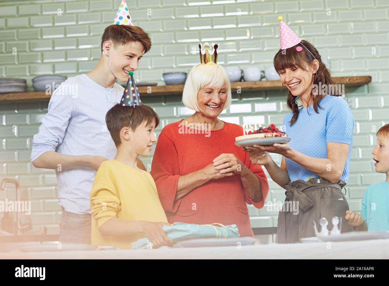Madre e figli celebrando alla nonna bithday nella loro cucina Foto Stock
