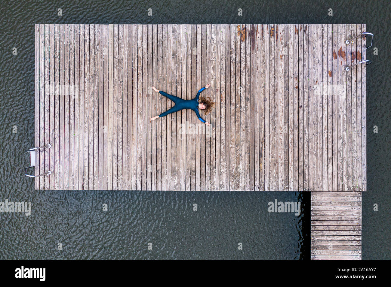 Vista aerea di una giovane femmina triatleta giacente sul pontile di un lago Foto Stock