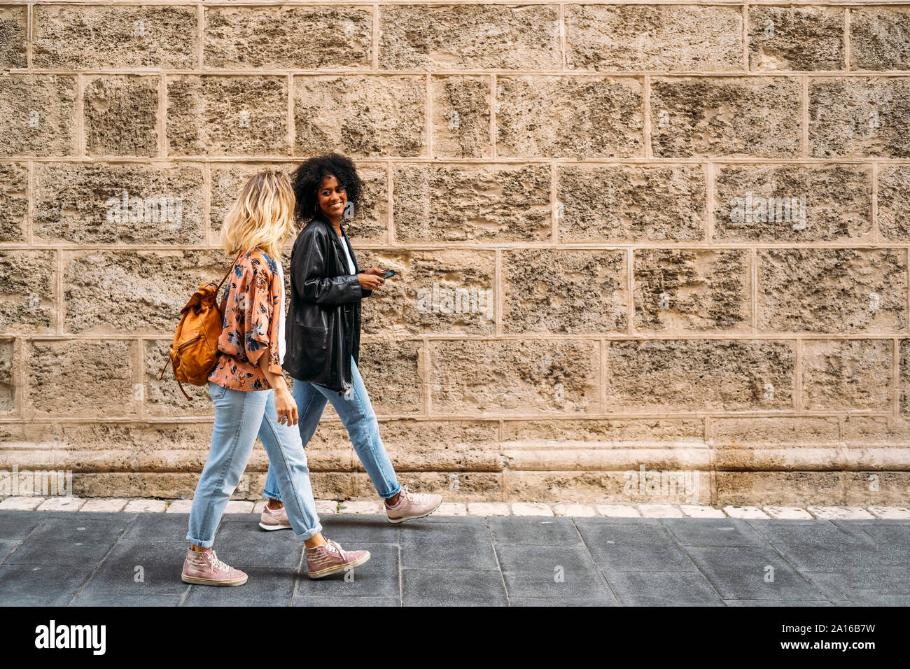 Multicultural felici donne passeggiate in città, utilizza lo smartphone Foto Stock
