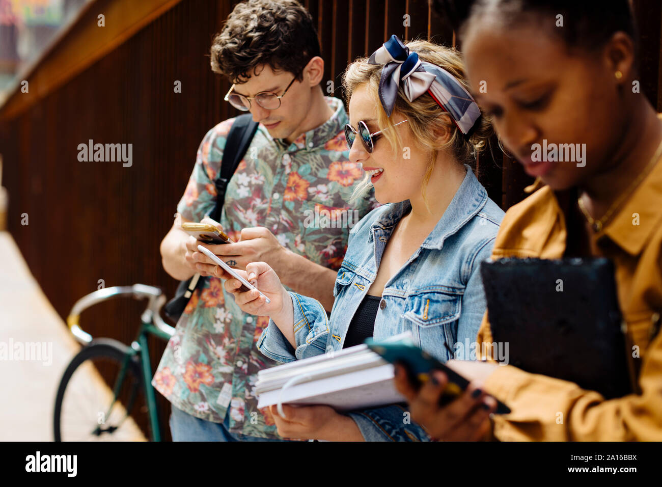 Gli studenti riuniti in un cortile, parlando, smartphone unsing Foto Stock