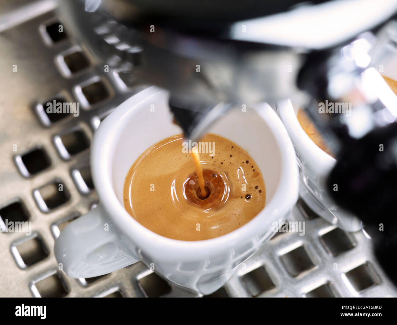 L'Espresso che fluisce in una tazza di espresso Foto Stock