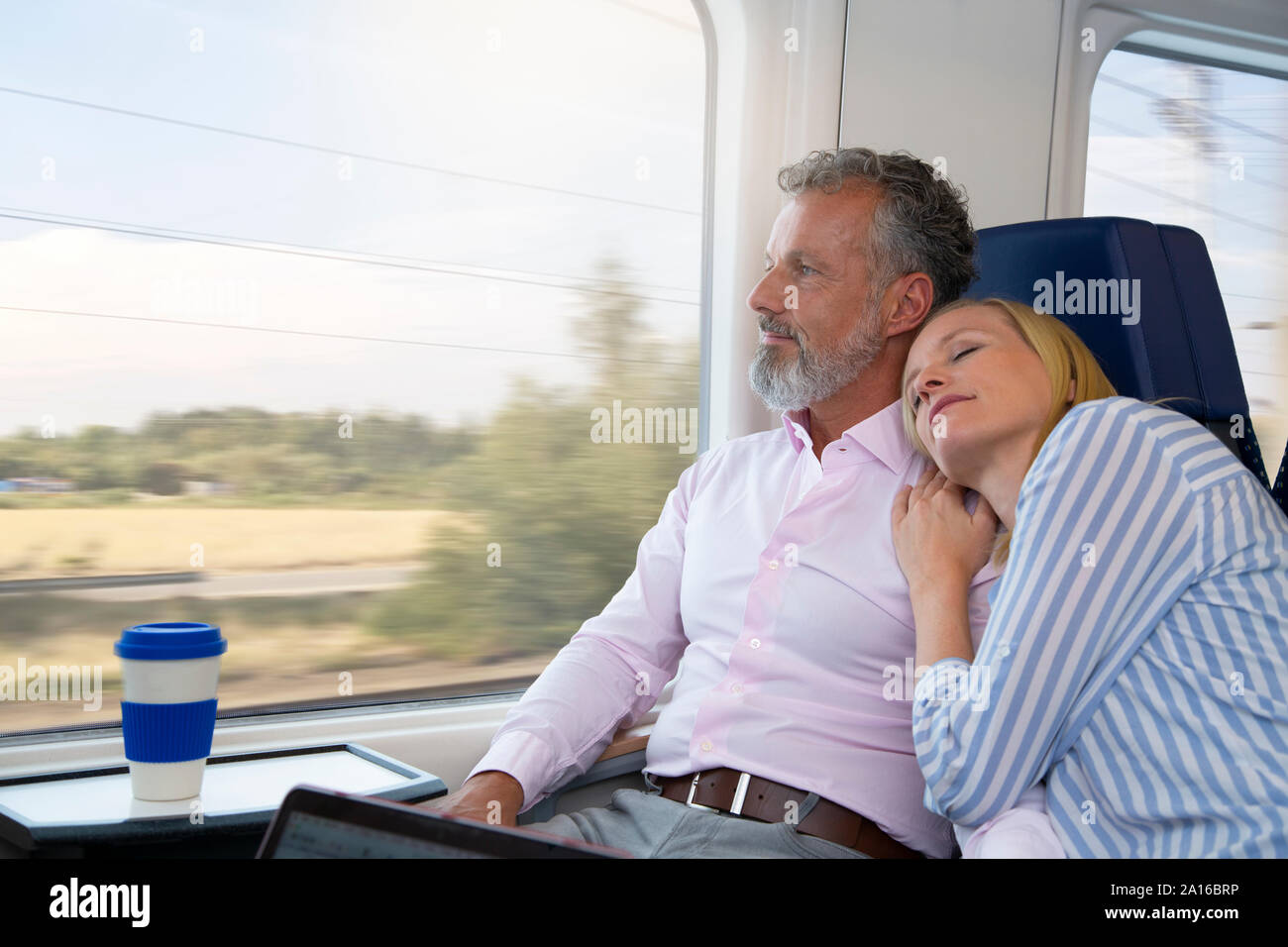 Coppia che viaggia in treno, donna appoggiata su uomini della spalla Foto Stock
