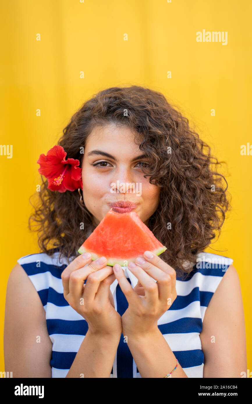 Ritratto di donna mangiare anguria, sfondo giallo Foto Stock