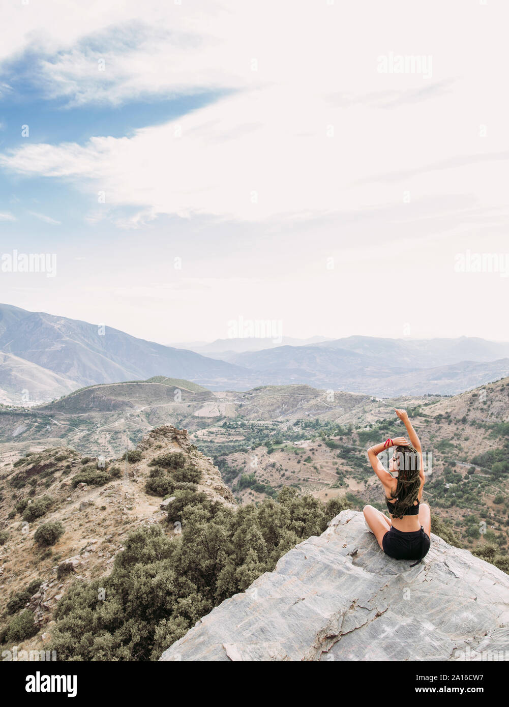 Vista posteriore dei giovani sportivi donna seduta sul punto di vista rocciose Foto Stock