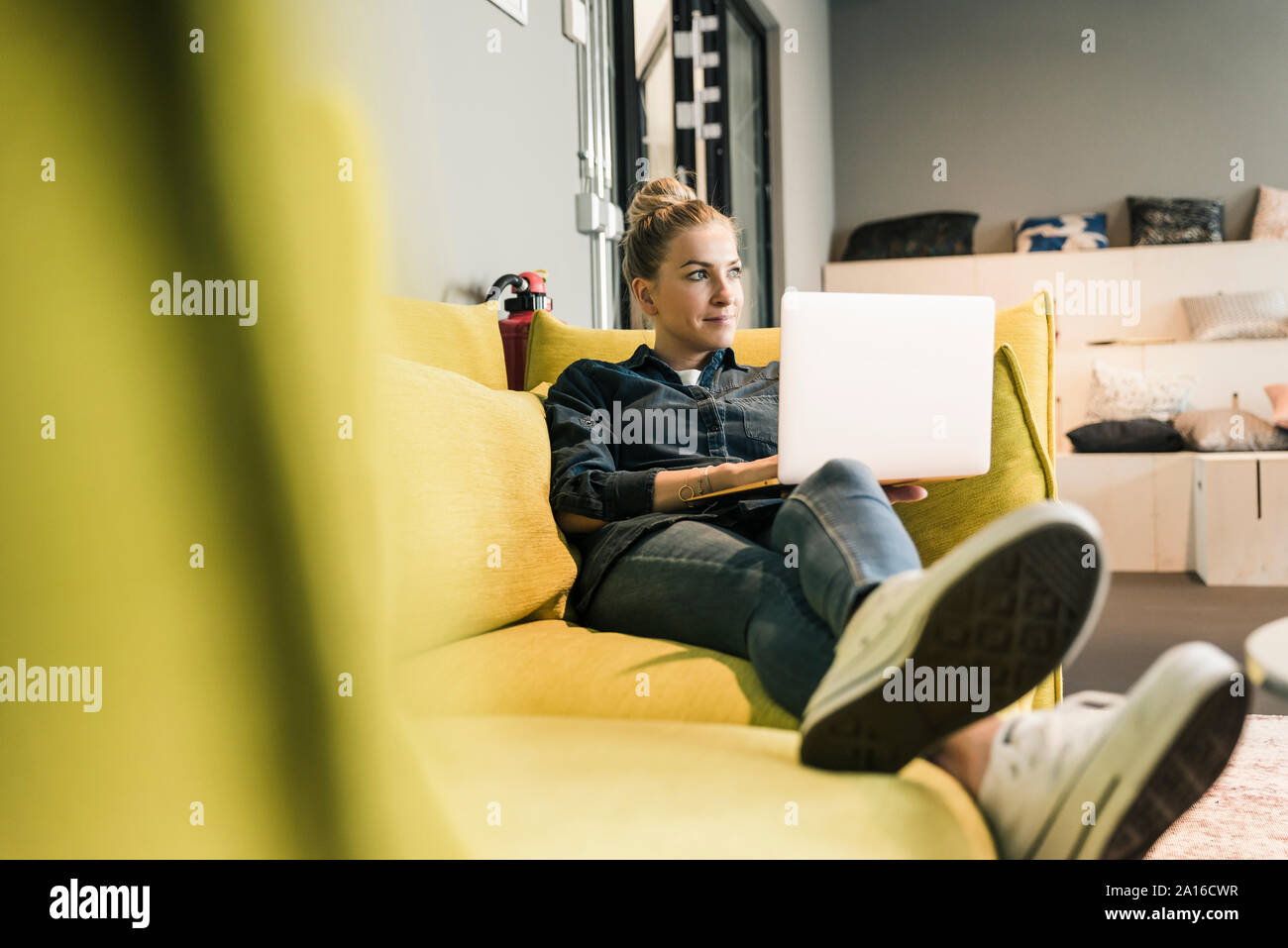 Casual imprenditrice utilizzando laptop sul lettino nella sala di office Foto Stock