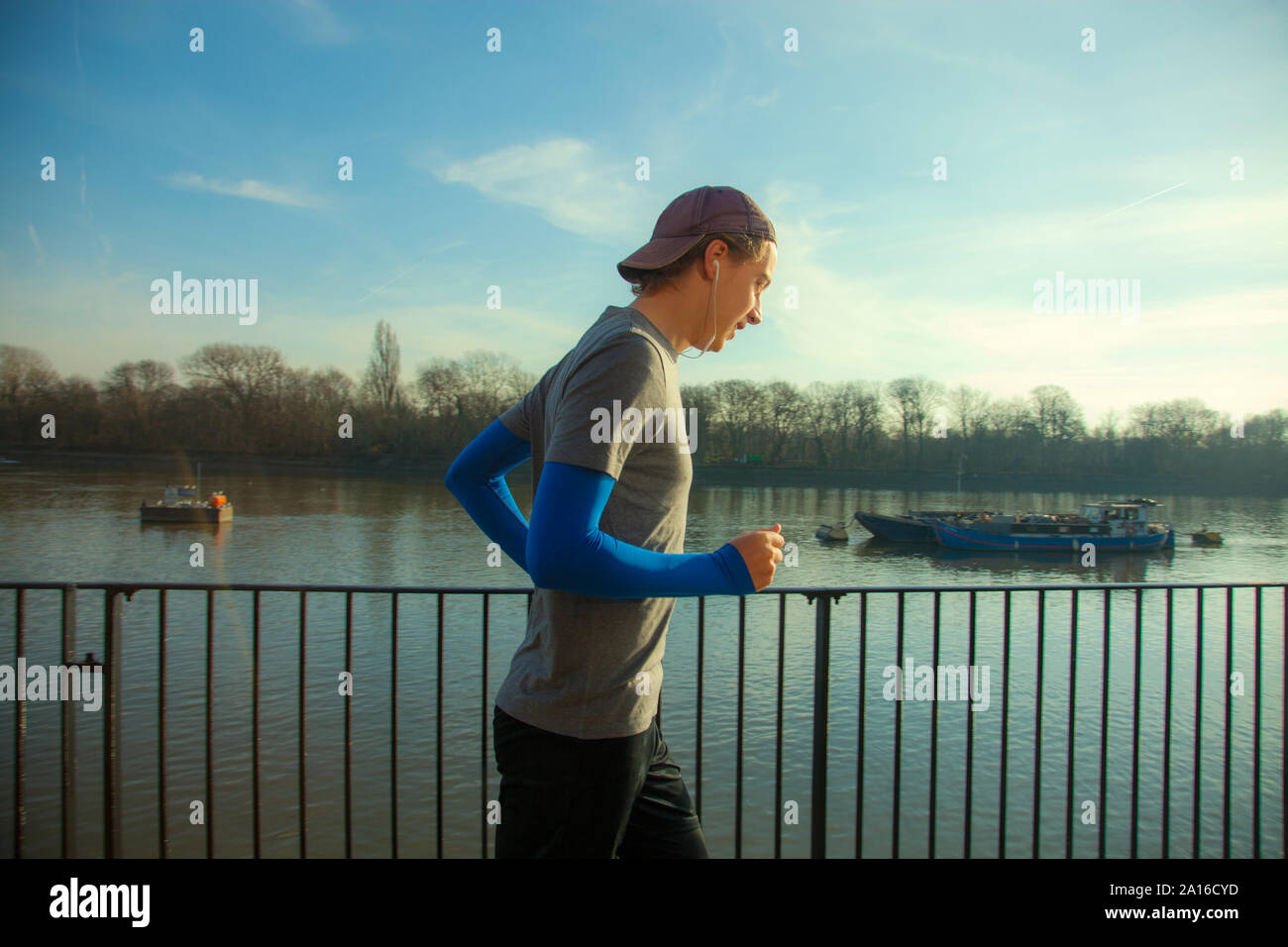 Giovane uomo fare jogging lungo il fiume Tamigi, London, Regno Unito Foto Stock