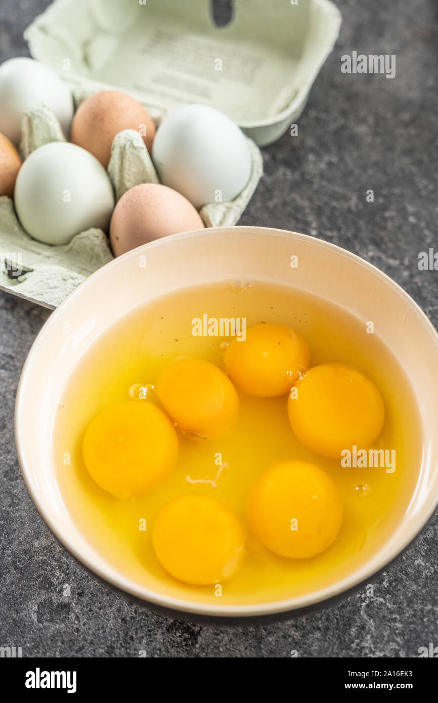 Organico fresco uova - sei in una scatola e da una mezza dozzina di già rotto in posizione aperta e in una ciotola Foto Stock