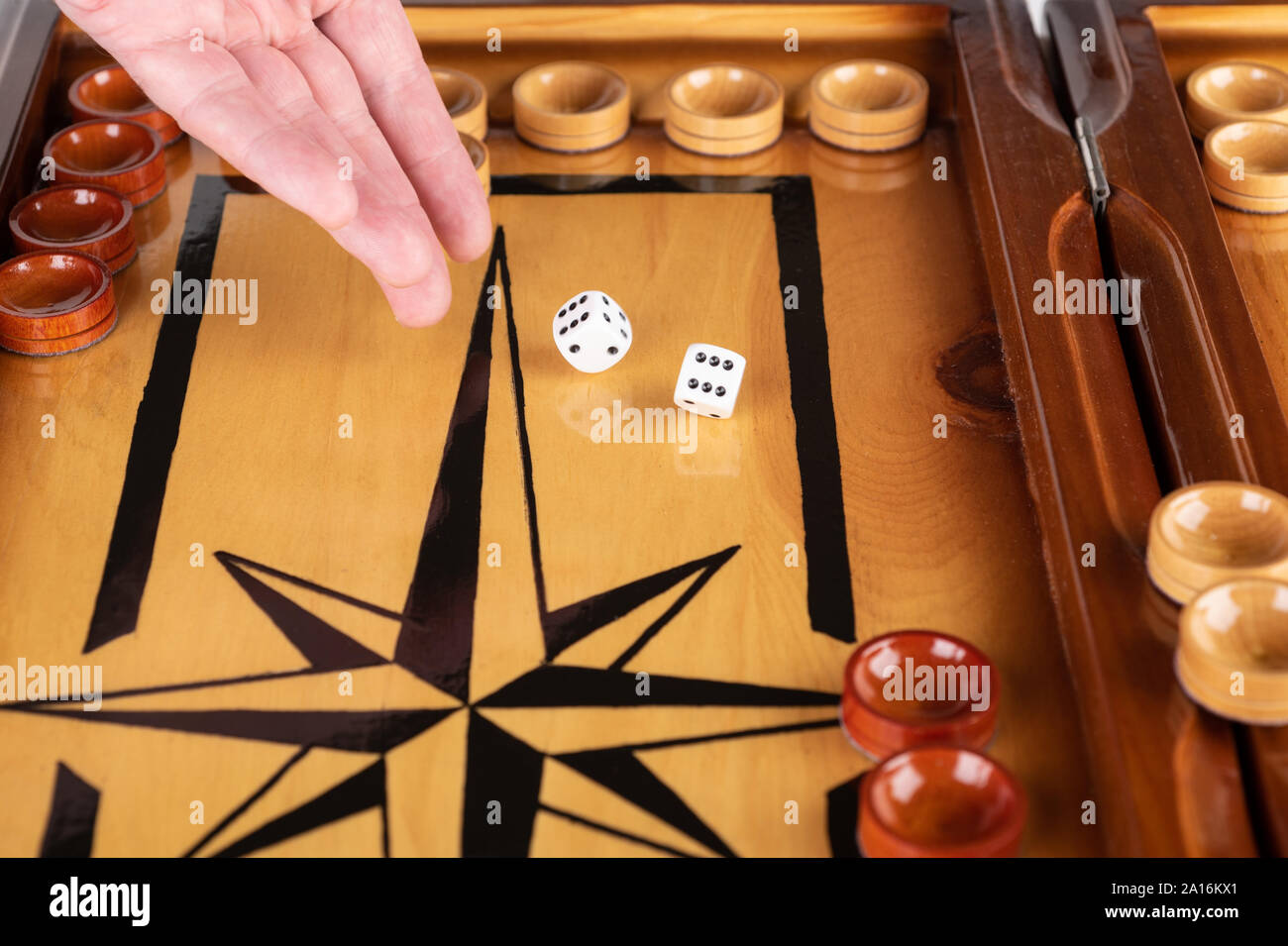 Una mano lancia dadi bianco su un bordo del backgammon. close up. Foto Stock