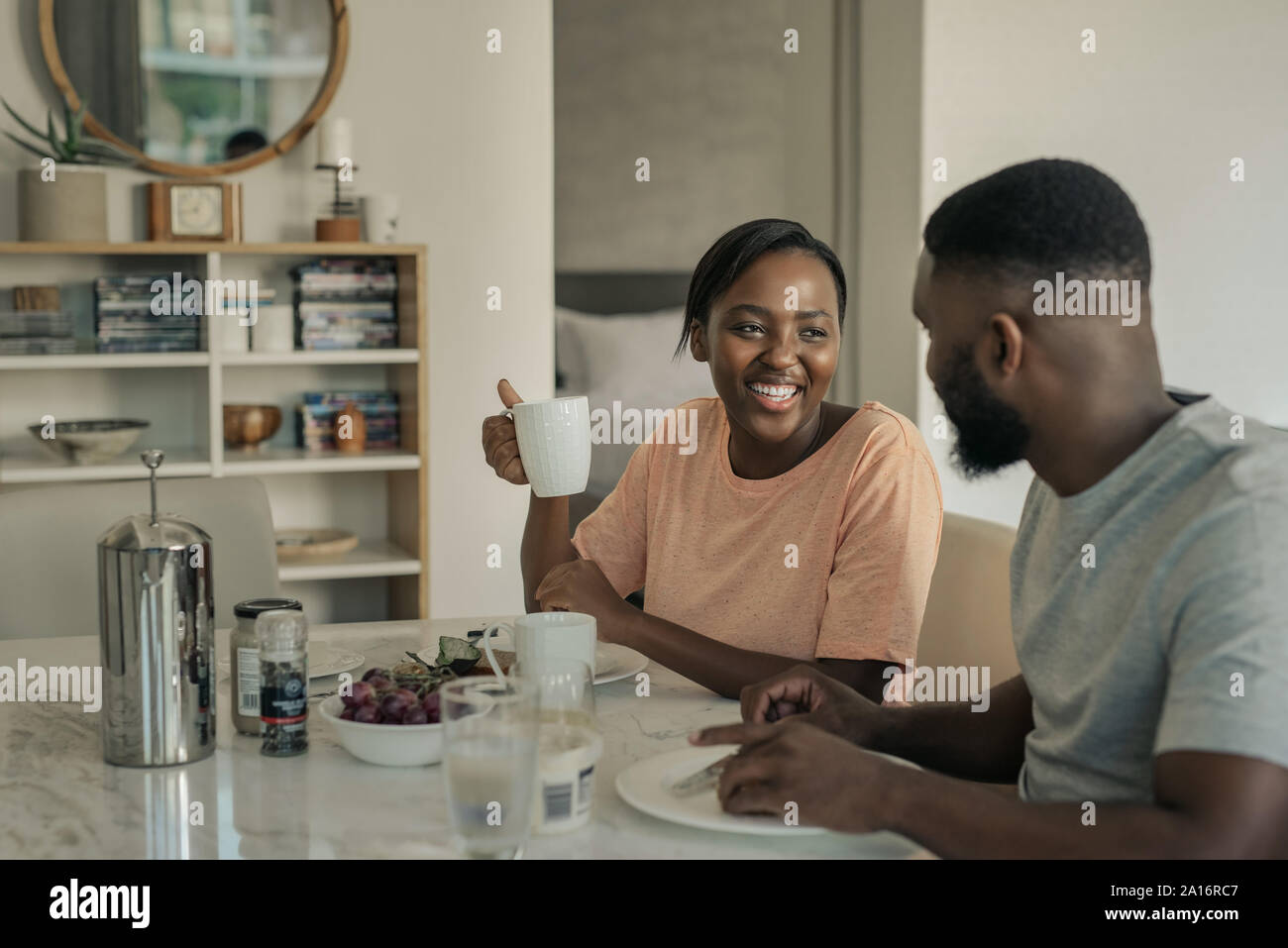 Ridendo giovane americano africano giovane gustando la prima colazione insieme a casa Foto Stock