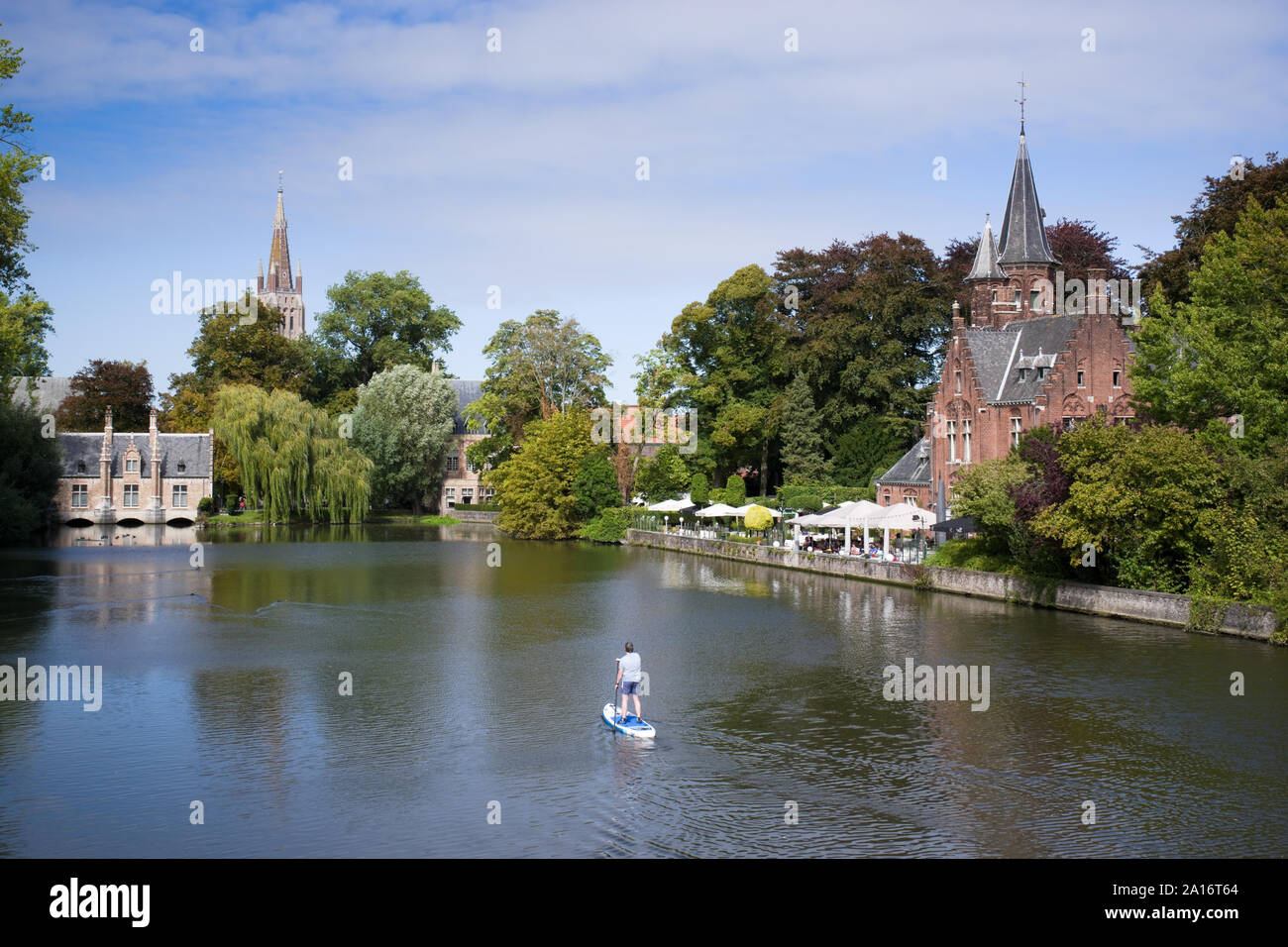 Un uomo paddleboards sul lago presso il parco Minnewater (amante di lago) in Bruges, Belgio. Foto Stock