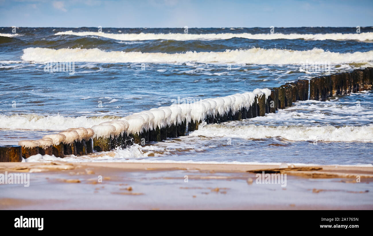 Spiaggia con un gelido frangiflutti in legno in una giornata di sole. Foto Stock