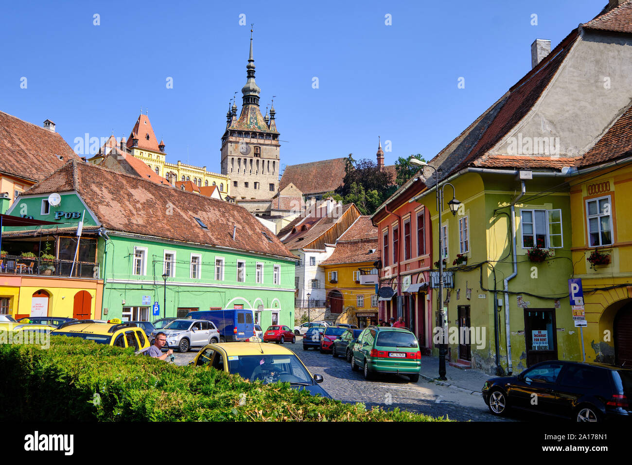 La piazza centrale di pietra in ciottoli street con case colorate all'entrata della cittadella, con la torre di porta in background. Sighisoara, Romania - Luglio Foto Stock