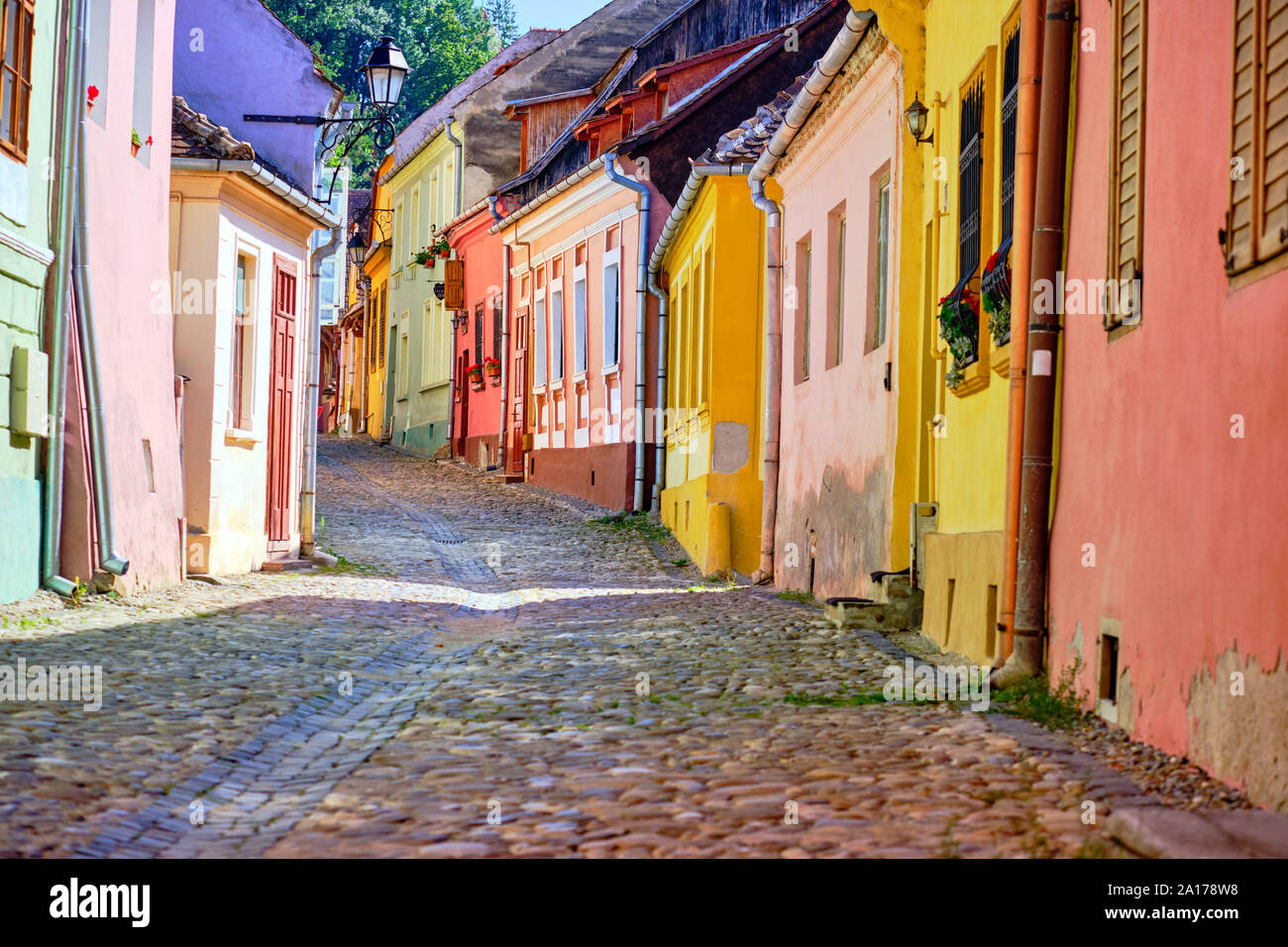 Conservato colorate facciate di case con strada acciottolata in salita in cittadella di Sighisoara, Romania. Sighisoara, Romania - Luglio 2019. Foto Stock