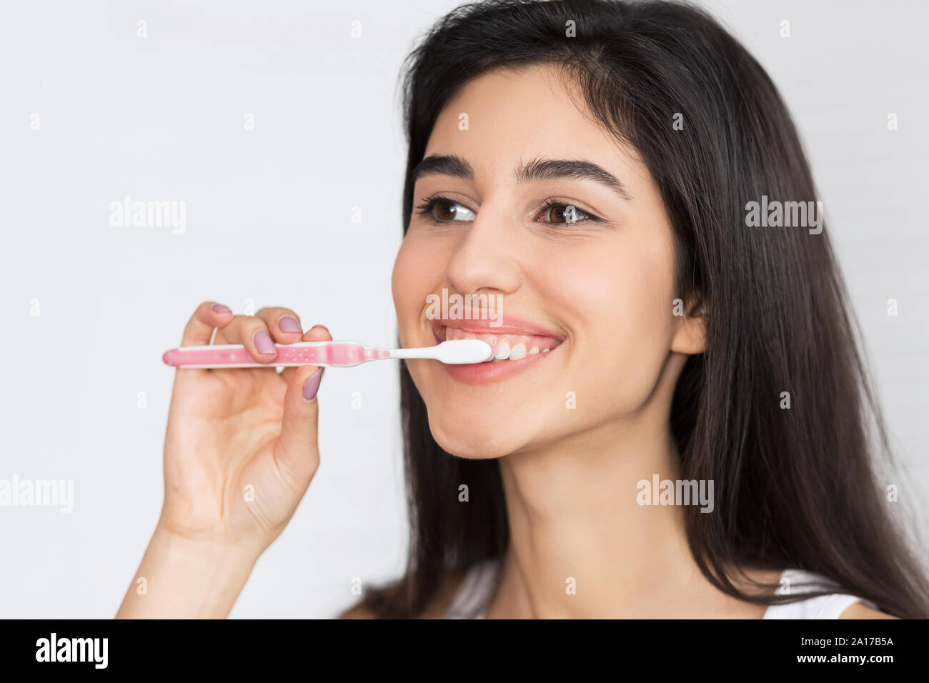Ragazza spazzolare i denti con spazzolino da denti, sfondo bianco Foto Stock