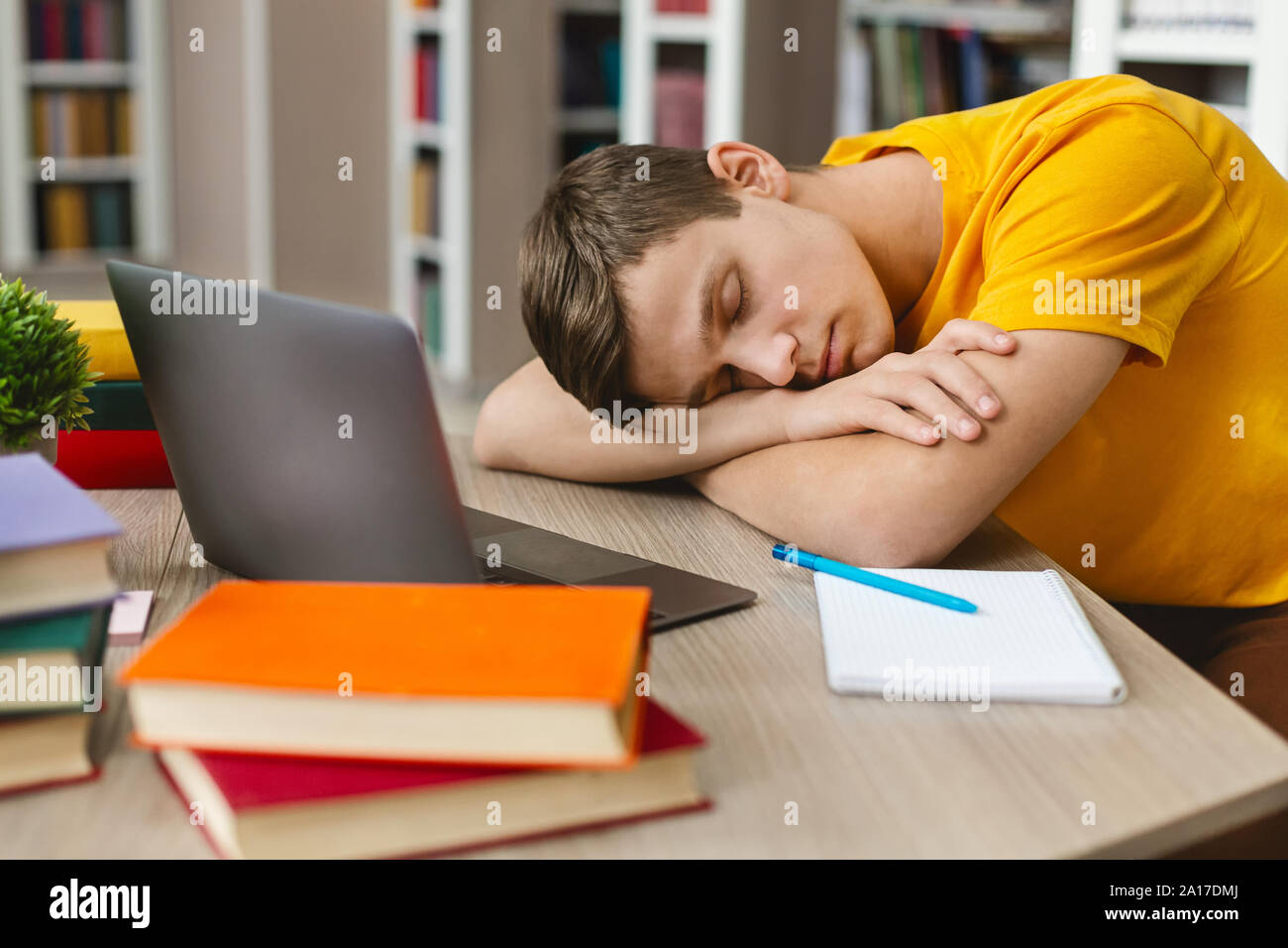 Esaurito studente di dormire sul posto di lavoro nella parte anteriore del computer portatile Foto Stock