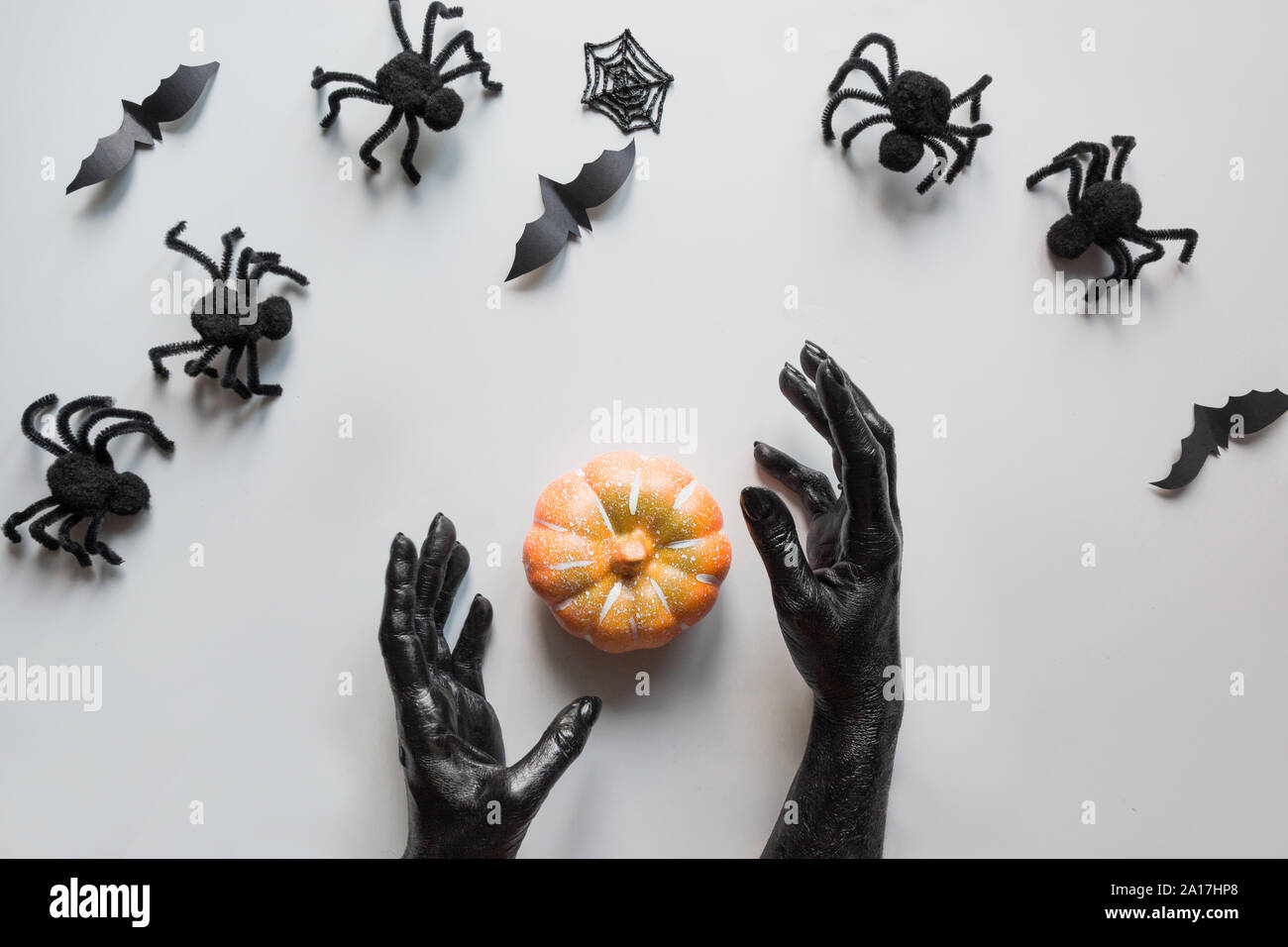 Halloween spider, zucca, bat, mani femminili ricoperto in vernice nera con decorazioni su sfondo grigio. Appartamento laico, vista dall'alto. Creative giorno di Halloween compo Foto Stock