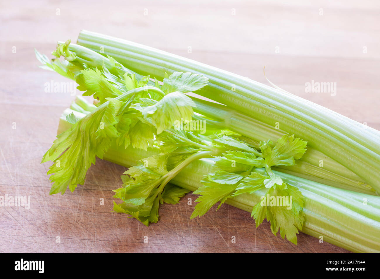 Una testa di sedano fresco su una superficie in legno Foto Stock