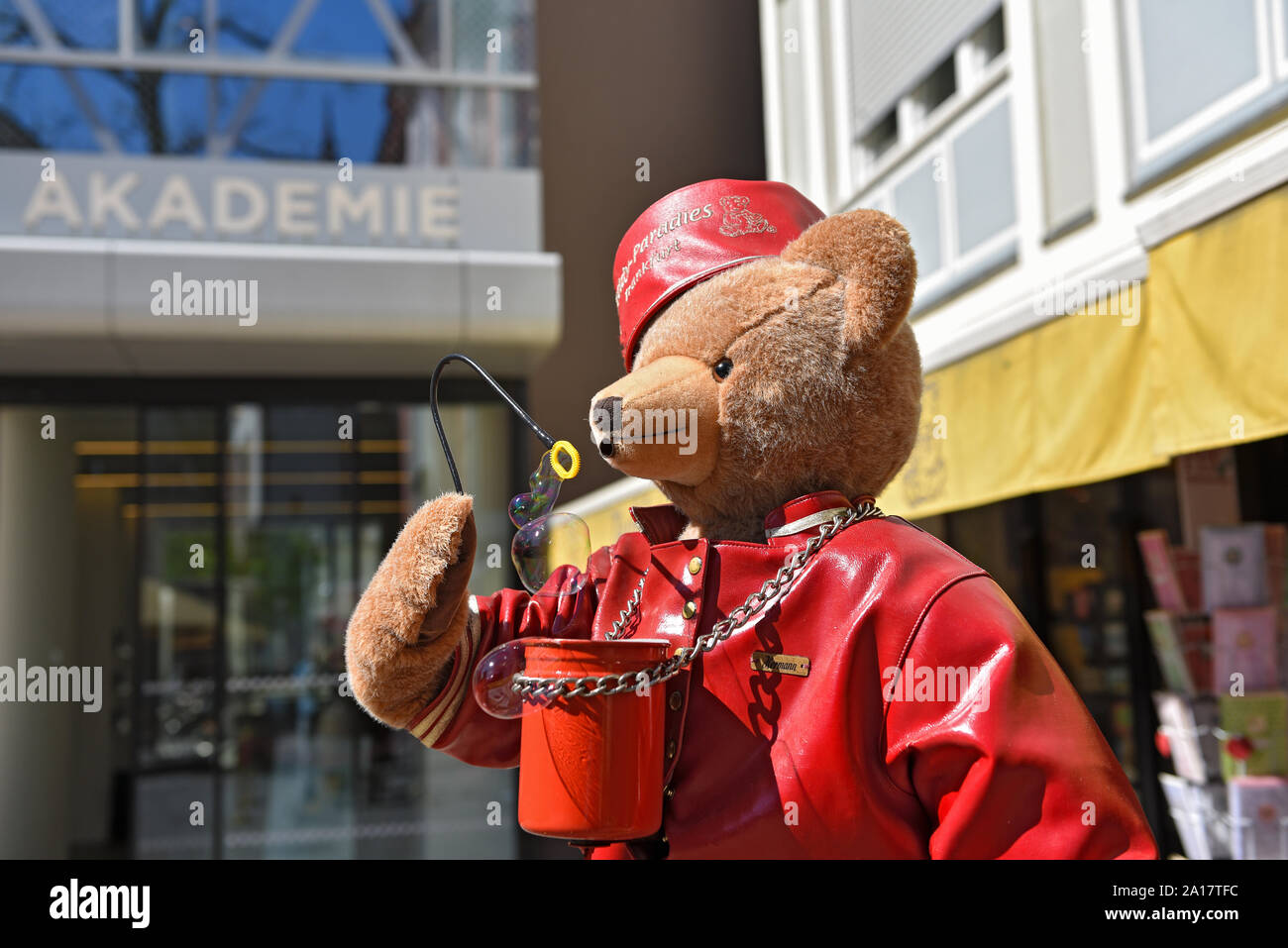 Grande orso di peluche con Red Hat e giacca di pelle soffia bolle di sapone in aria Foto Stock