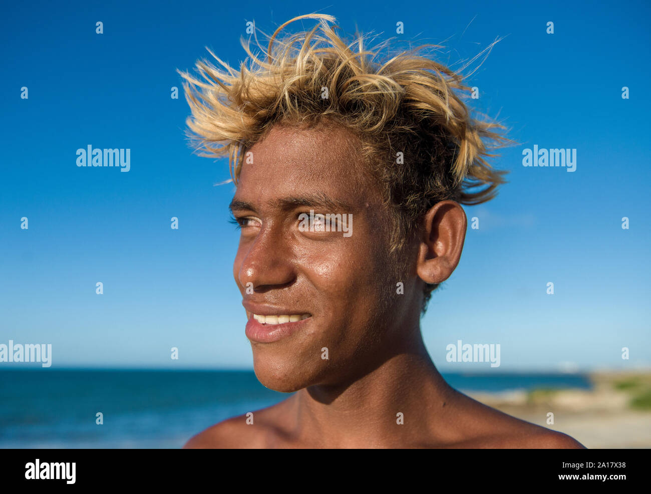 Ragazzo brasiliano sulla riva del mare con capelli tinti e pelle marrone Foto Stock