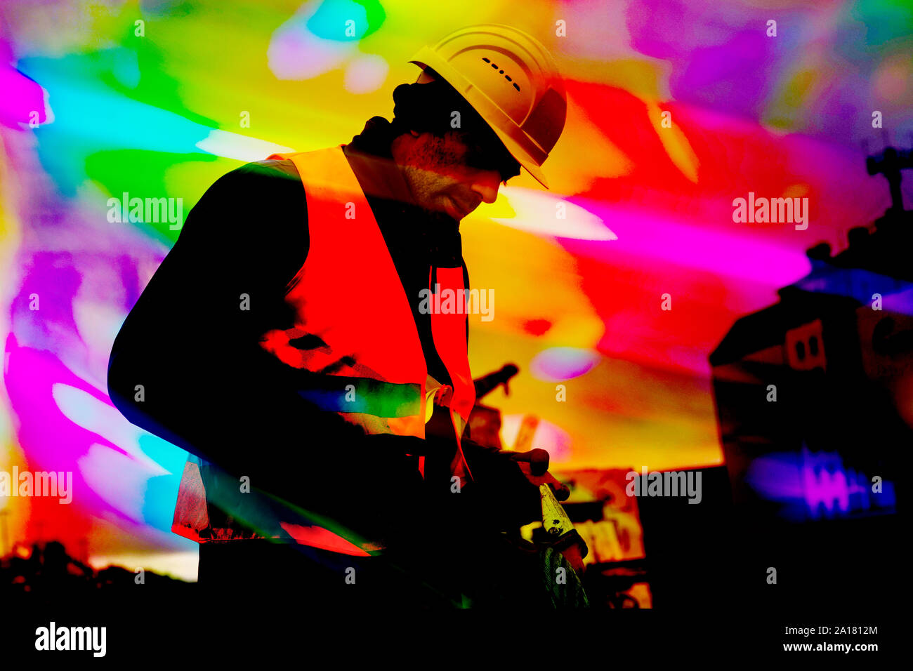 Lavoratore con casco lavorando e strisce colorate di luce Foto Stock