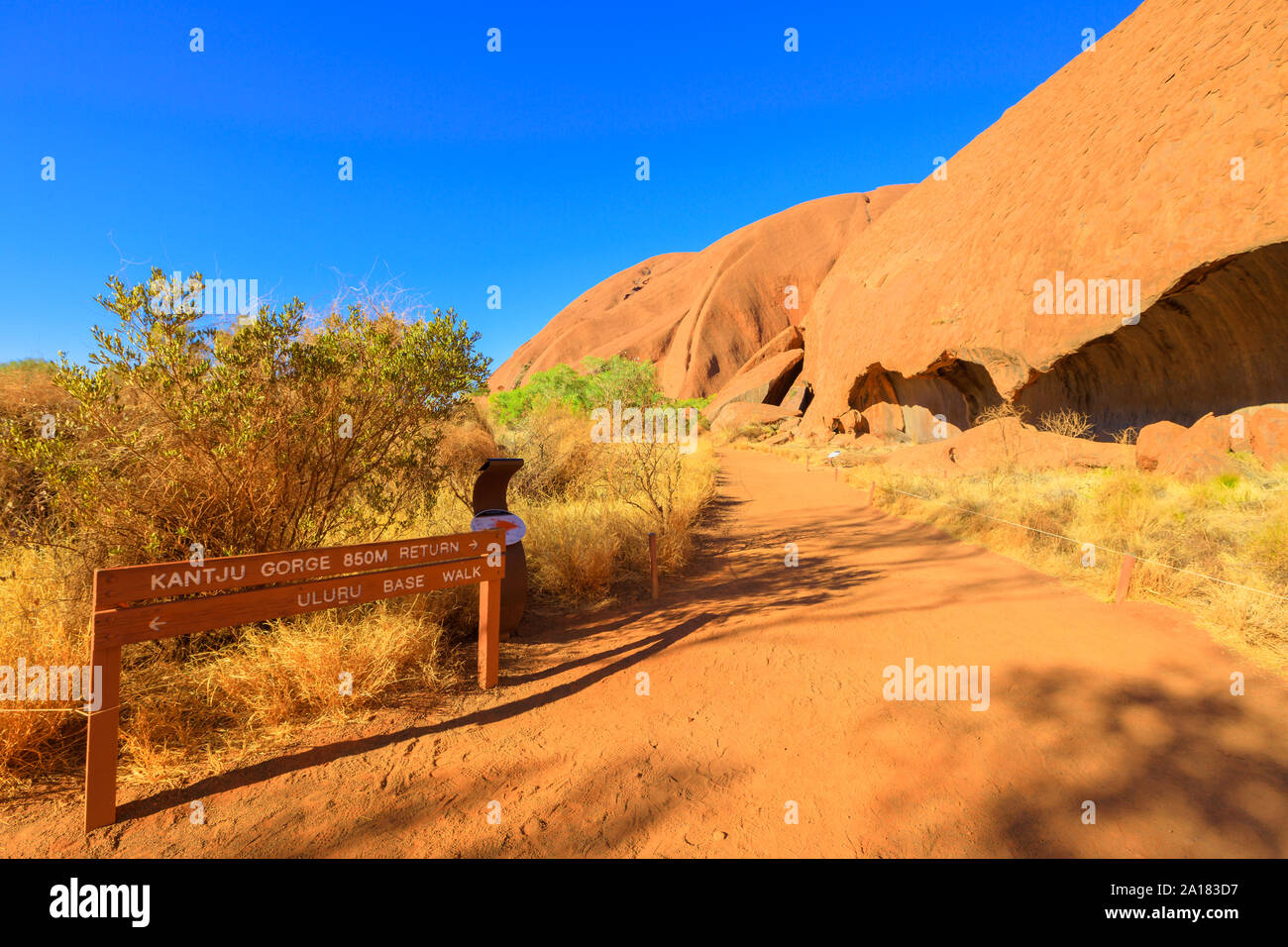 Base di Uluru a piedi e Kantju Gorge segno e una serie di grotte all'interno della roccia lungo il sentiero di sabbia, utilizzato da Mala popolo Anangu antenati nell'Uluru-Kata Tjuta Foto Stock