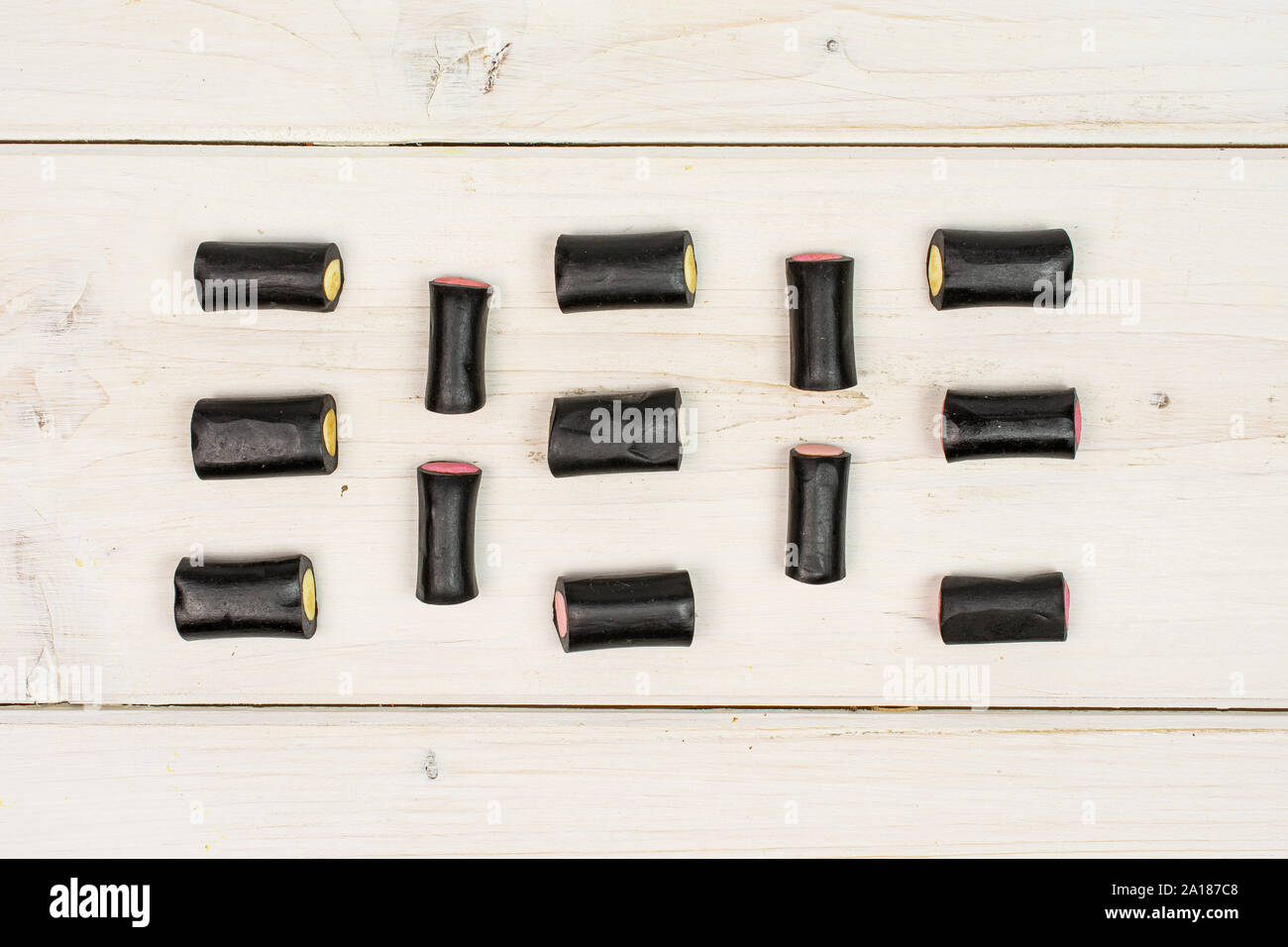 Sacco di tutto il dolce di liquirizia nera candy flatlay su legno bianco Foto Stock