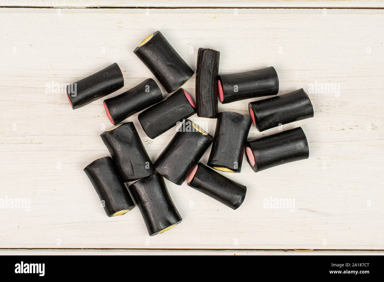 Sacco di tutto il dolce di liquirizia nera candy flatlay su legno bianco Foto Stock