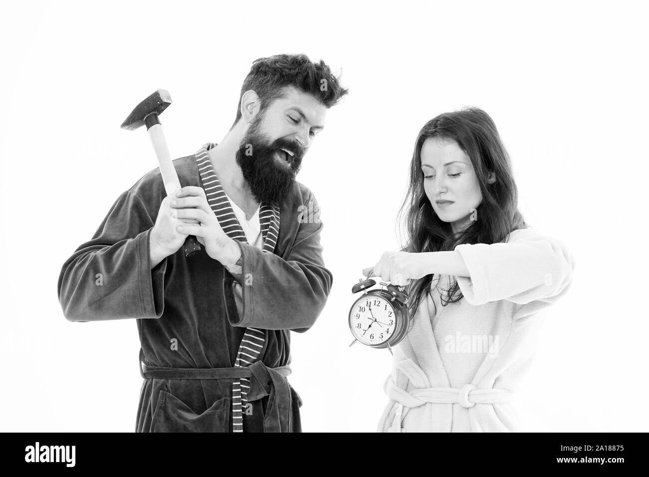 Rabbia e odio. La mattina presto l'ansia. Sbarazzarsi di fastidiosi sveglia. Coppia di accappatoi andando a distruggere la sveglia e rimanere a casa propria. Regole di rottura. Uomo con un martello battere sveglia. Odioso suono. Foto Stock