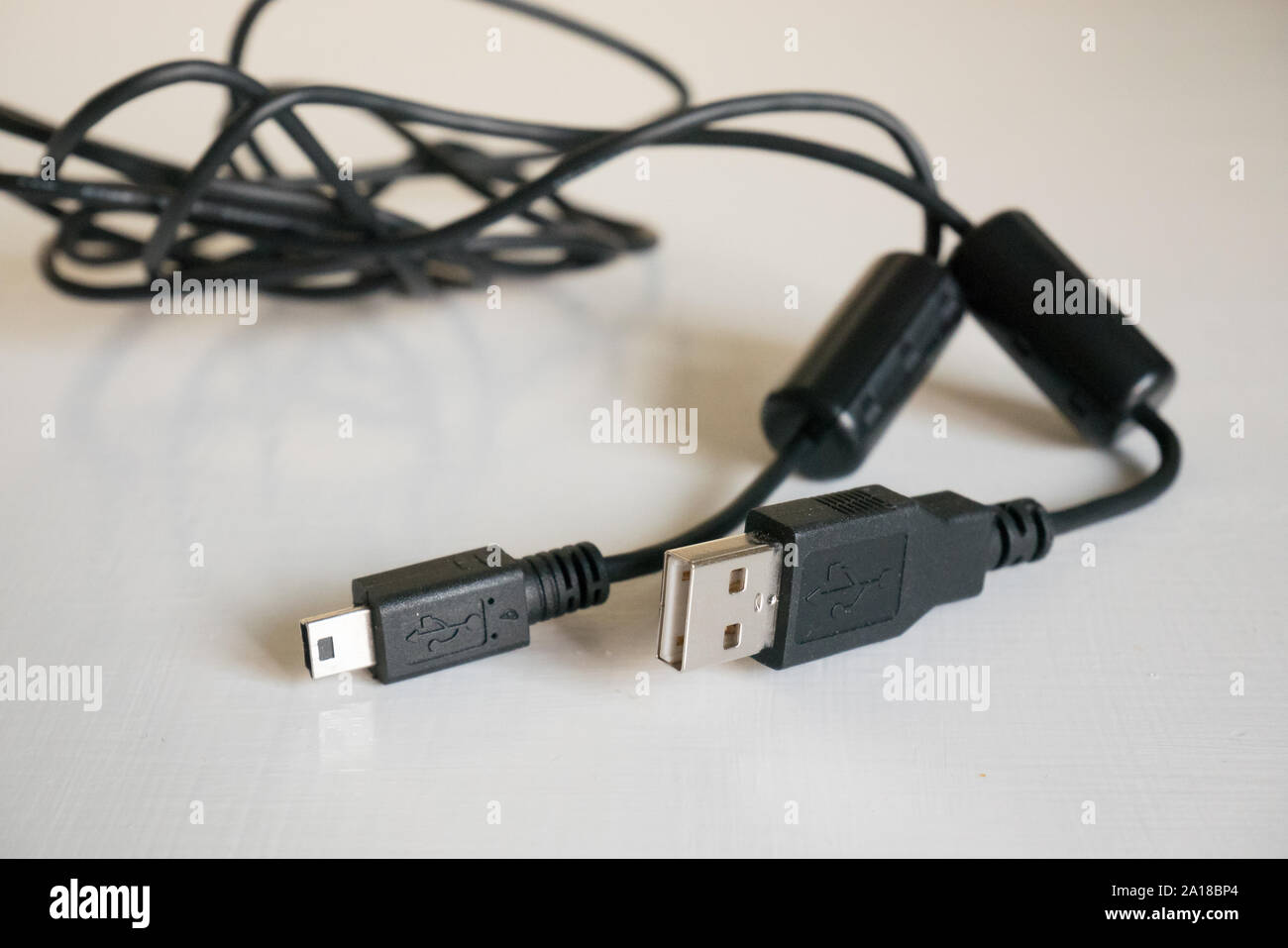 Da USB a mini USB del cavo su un tavolo bianco Foto Stock