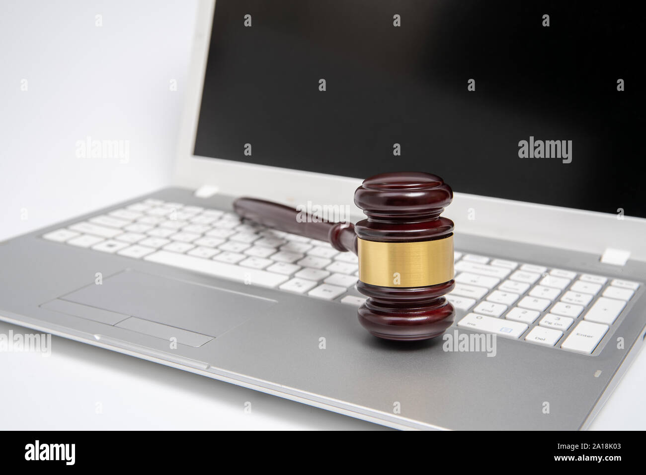 Giudice in legno martello su un argento computer laptop, cyber legge o asta online concetto. Foto Stock