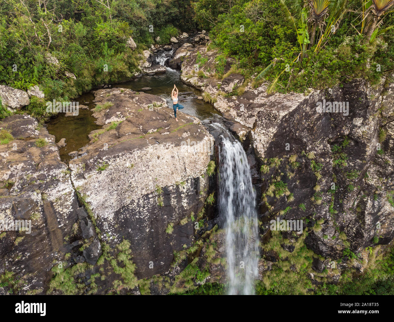 Attiva donna sportivo relax nella natura, praticare yoga su alta clif da 500 piedi a cascata Black River Gorges national park in paradiso tropicale Foto Stock