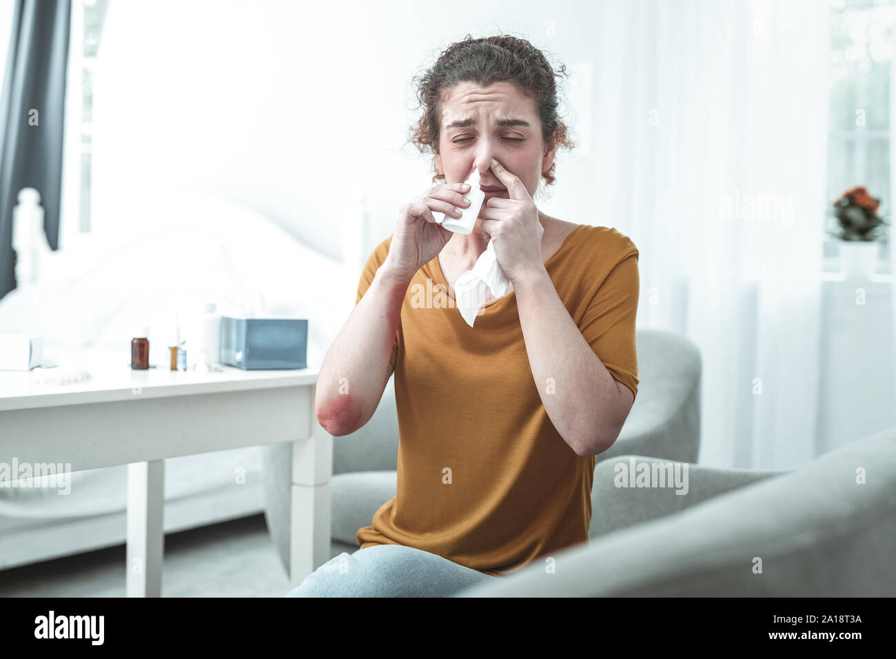 Curly donna con arrossamento sul gomito mediante spray nasale Foto Stock