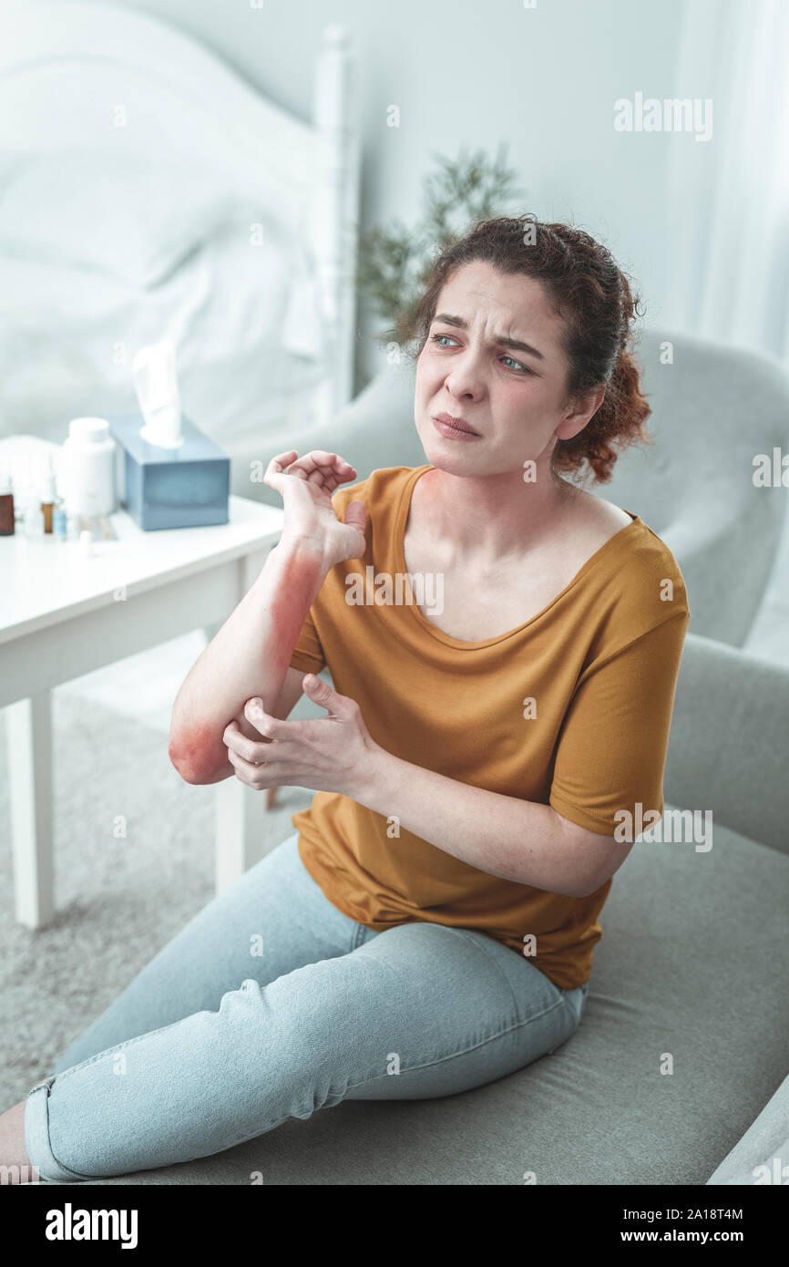 Donna che indossa jeans e maglietta arancione avente graffi sul braccio Foto Stock