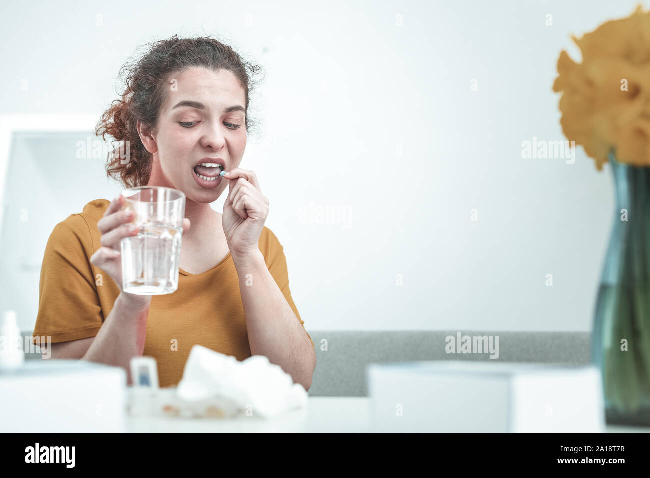 Donna che mantiene un bicchiere di acqua mentre sta assumendo il farmaco allergia Foto Stock