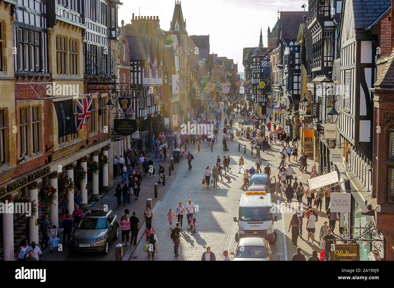 Iconico Eastgate Street a Chester con il tradizionale stile Tudor House e le persone aventi una passeggiata. I raggi del sole creano un atmosfera speciale. Foto Stock