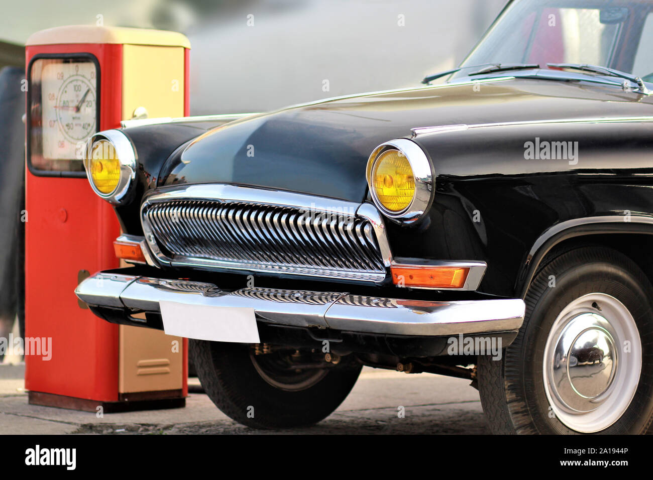 La parte frontale di un vecchio vintage auto nera con sfondo sfocato vicino retrò rosso stazione di gas Foto Stock