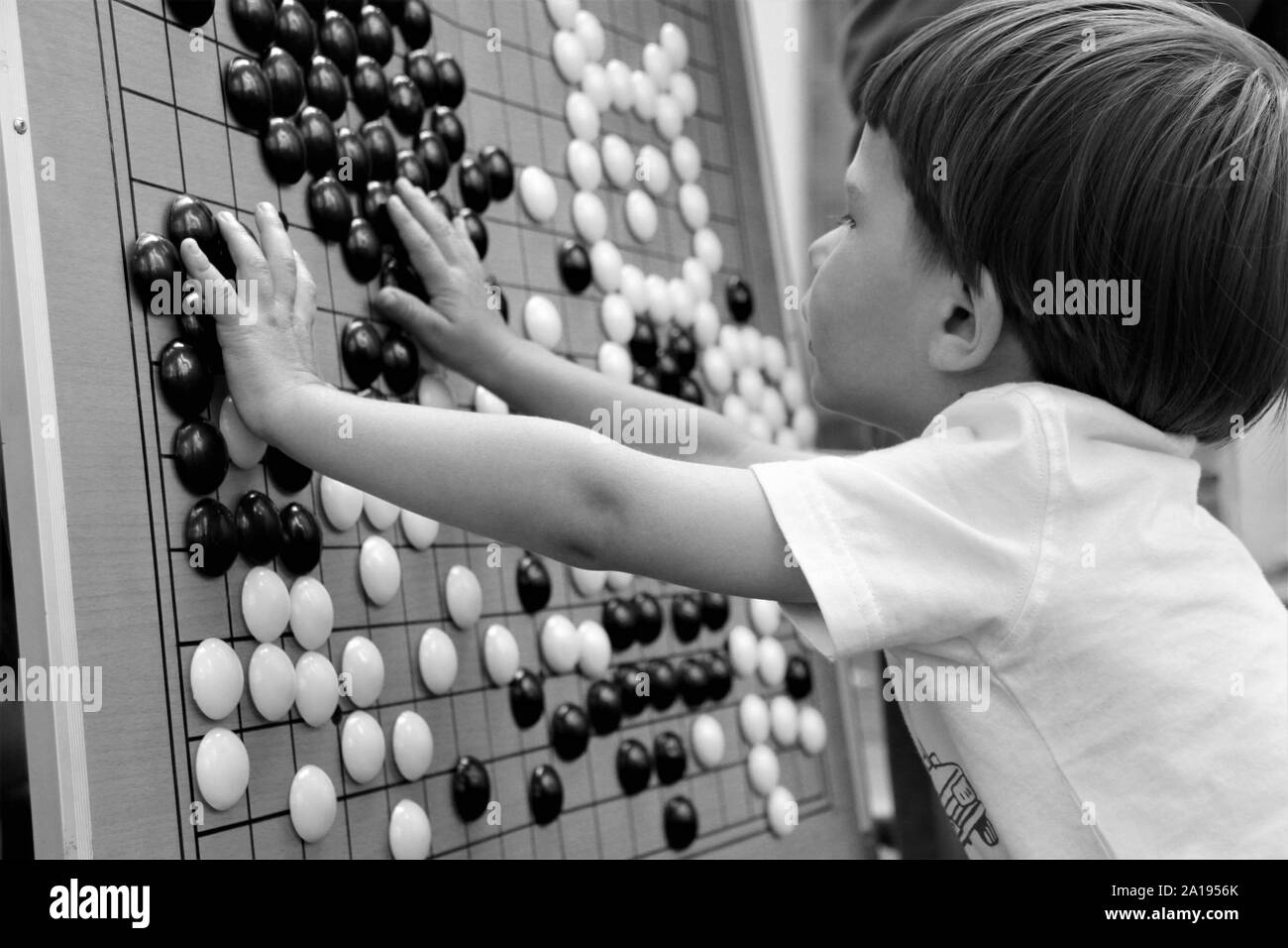 Ragazzo giocando gioco cinese Go, vicino, in bianco e nero Foto Stock