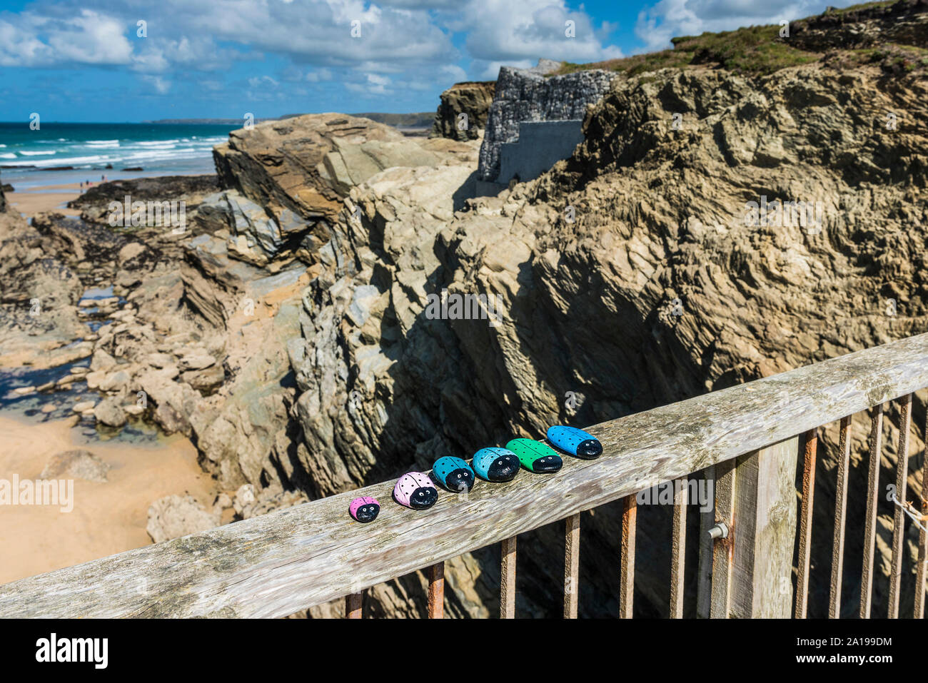 Una serie di dipinti a mano i ciottoli disposti sulla passerella che collega la terraferma e Porth Island a Porth Beach in Newquay in Cornovaglia. Foto Stock