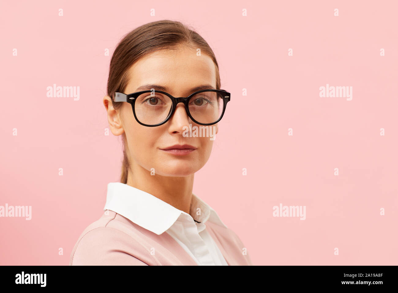 Ritratto di giovane bella donna che indossa occhiali e guardando la telecamera isolata su sfondo rosa Foto Stock