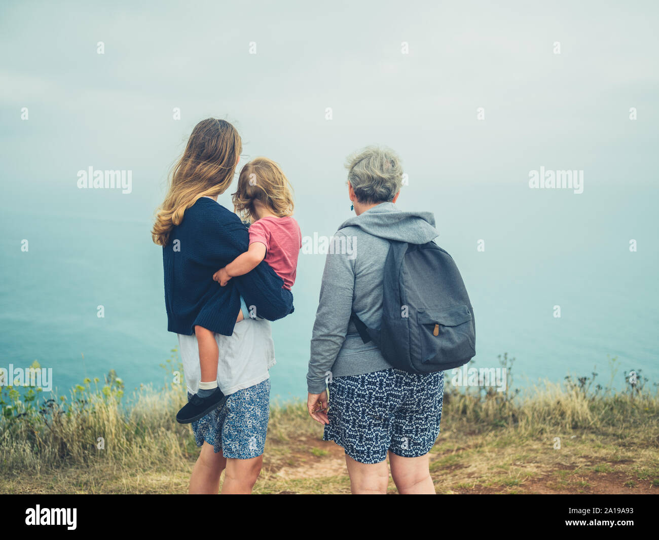 Una vera famiglia di madre e nonna e bimbo in piedi nella nebbia dal mare Foto Stock