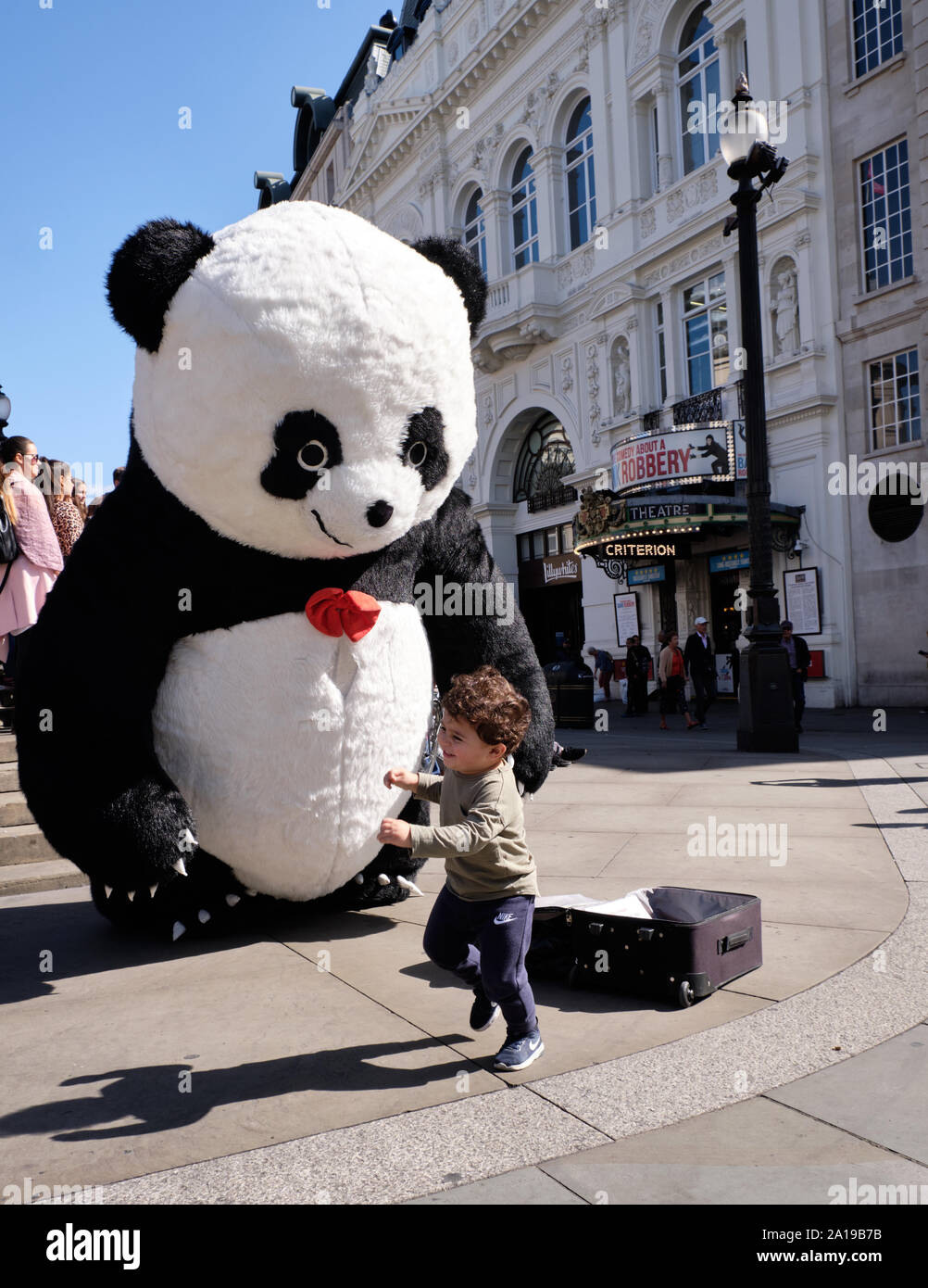 Piccolo bambino di scappare da Street performer vestito di panda gigante suit a piccadilly circus Foto Stock