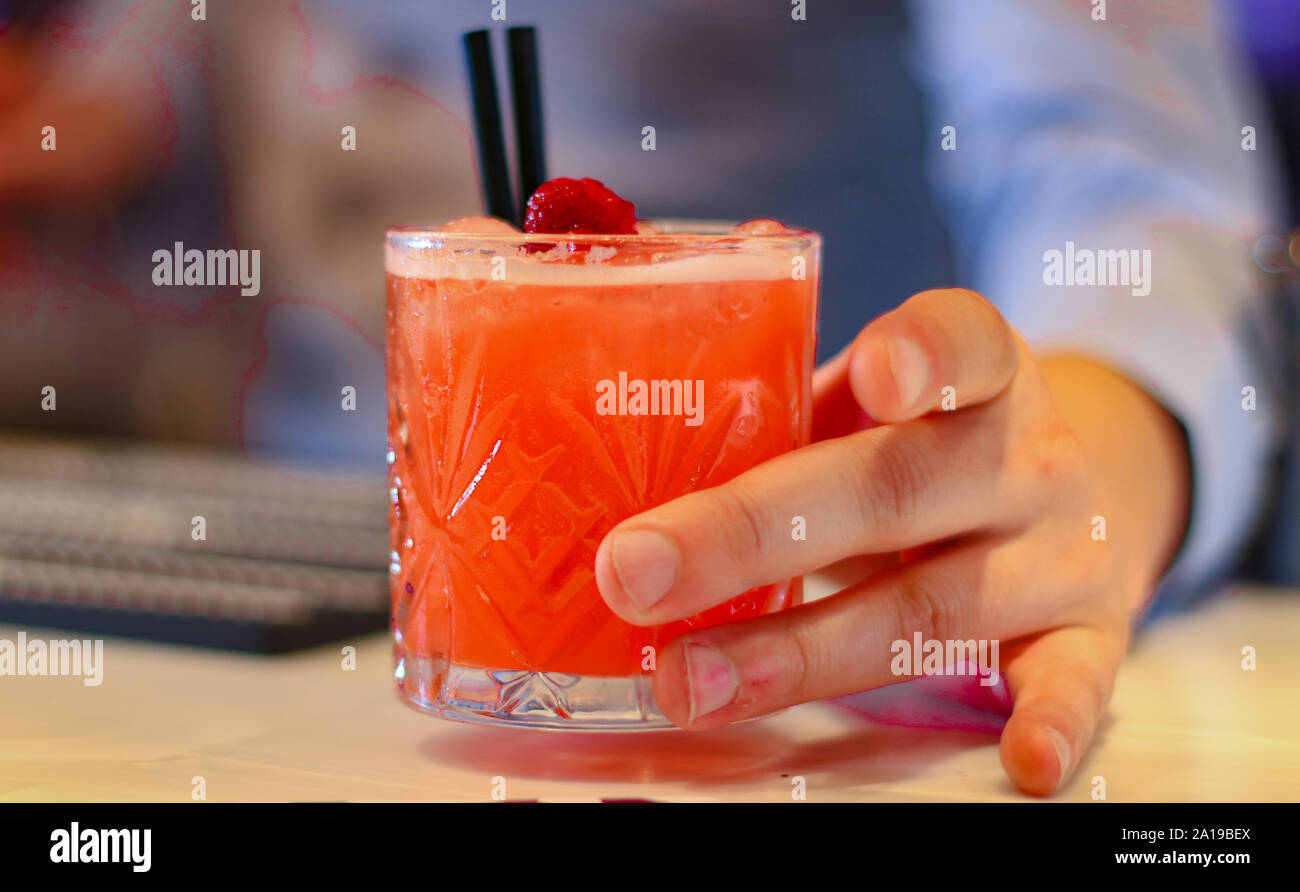 Il Barista serve orange cocktail alcolico in un bar. Primo piano di un barman che serve cocktail di frutta. Foto Stock