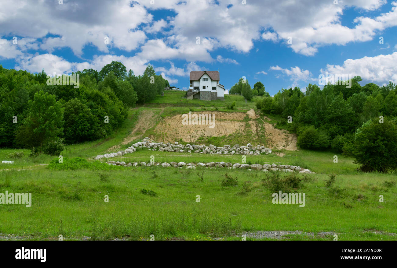 Casa sulla cima di una collina circondata di alberi verdi Foto Stock