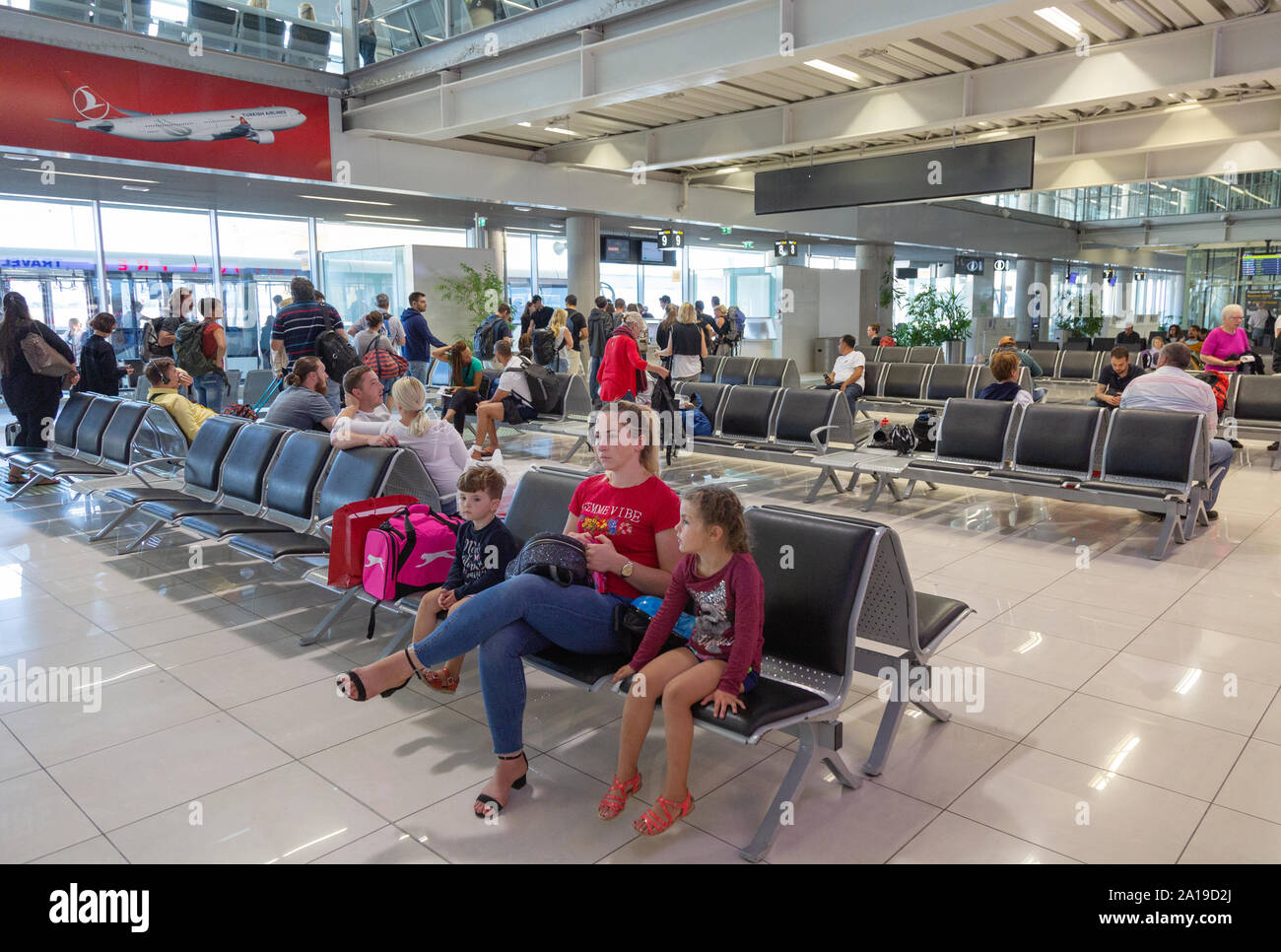 Aeroporto di Dubrovnik - una famiglia con bambini seduti nella sala partenze all'interno del terminale, Dubrovnik Aeroporto locale Croazia Europa Foto Stock