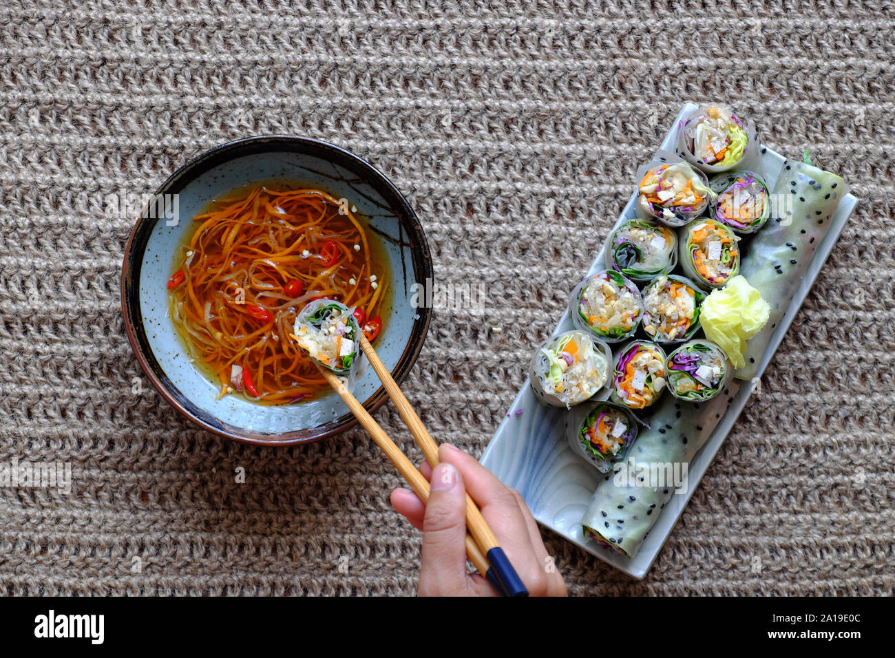 Vista superiore persone mangiare vegetariano a fette carta in rotoli di riso con salsa di verdure colorate rendono piatto vegano che sana e deliziosa Foto Stock