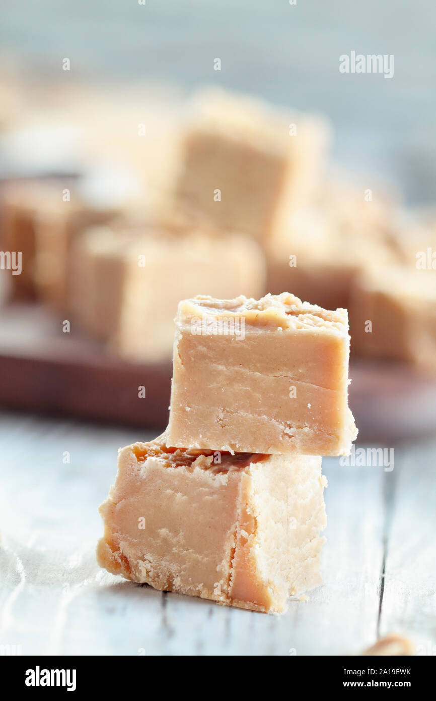 Piazze di deliziosi piatti fatti in casa, burro di arachidi fudge su una tavola in legno rustico sfondo. Messa a fuoco selettiva su caramelle impilate con sfondo sfocato. Foto Stock